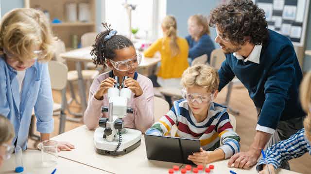 Des élèves avec un microscope et une tablette lors d'un atelier de sciences dans une classe