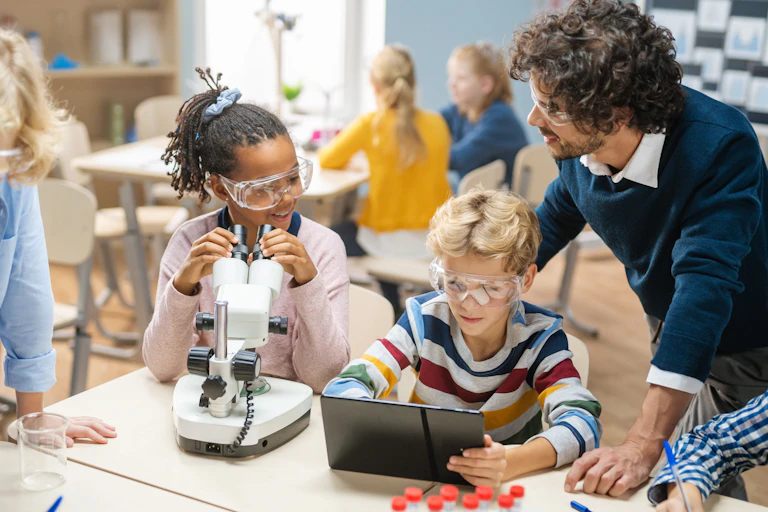 Des élèves avec un microscope et une tablette lors d'un atelier de sciences dans une classe