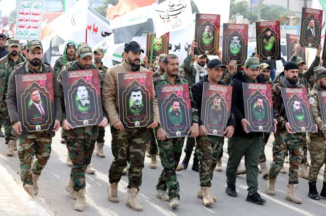Armed members of Iran's Quds force carrying pictures of their dead comrades after Feb 2 US airstrikes in Iraq.
