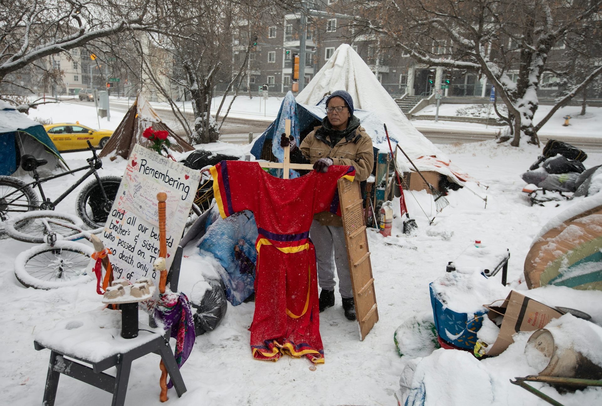 An Indigenous person stands defiantly in a snowy encampment.