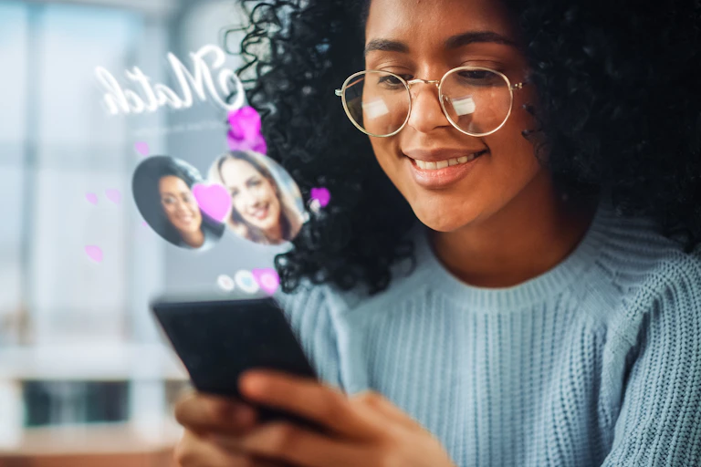A young woman smiles and looks at her phone, while an augmented reality dating app 'match' notification displays in the air above her phone
