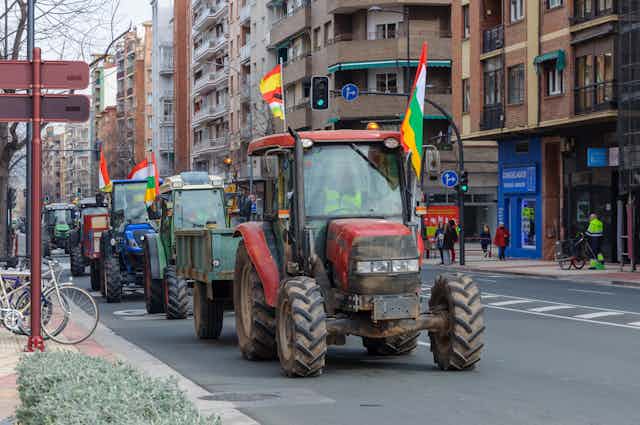 Fila de tractores avanzando por la calle de una ciudad.