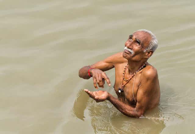 Older adult man taking a dip in the Ganges