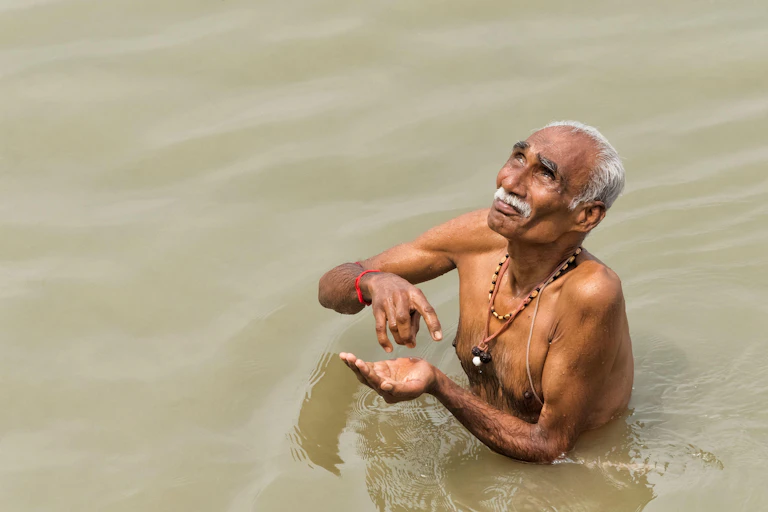 Older adult man taking a dip in the Ganges
