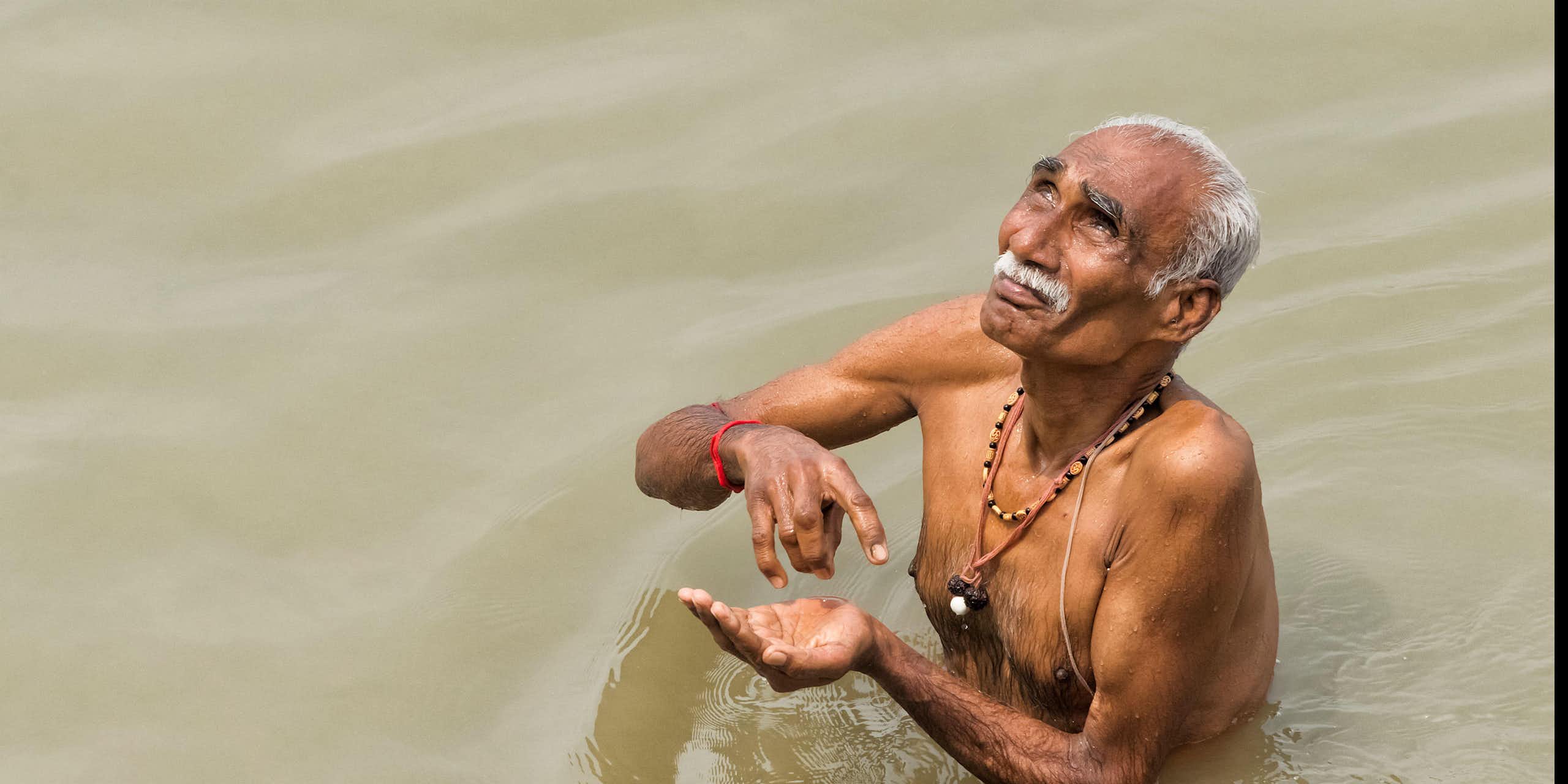 Older adult man taking a dip in the Ganges