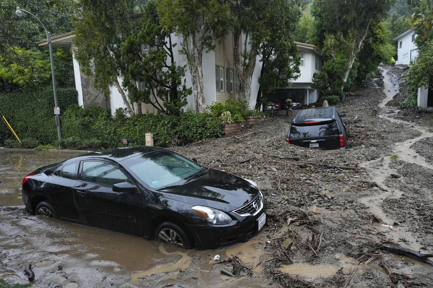 Two cars are trapped up to their widows in a mudslide that poured through a Los Angeles neighborhood. One car is parked in its driveway,
