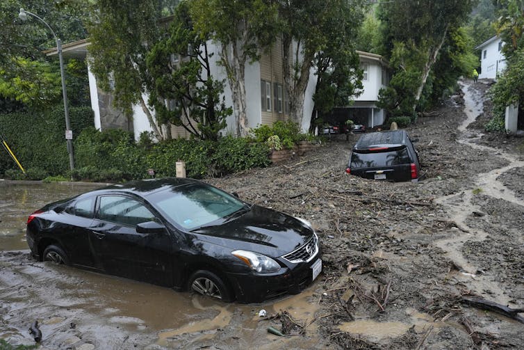 Two cars are trapped up to their widows in a mudslide that poured through a Los Angeles neighborhood. One car is parked in its driveway,