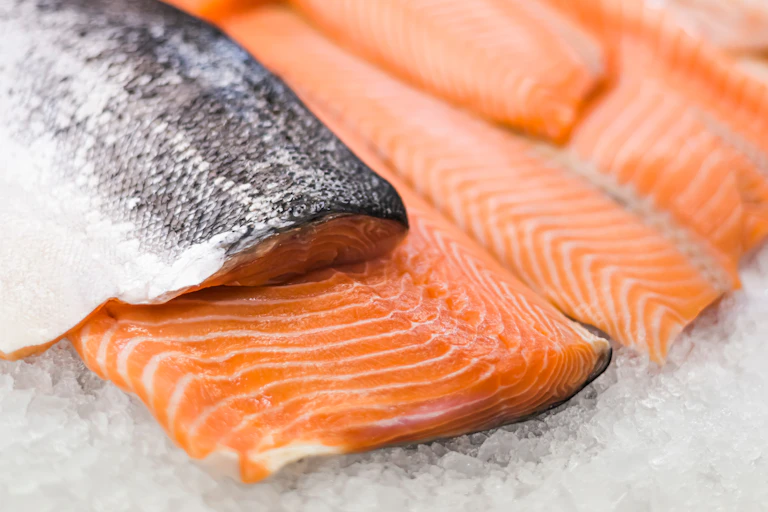 Bright orange salmon steaks cut, some with silver fish scales, laid out on ice
