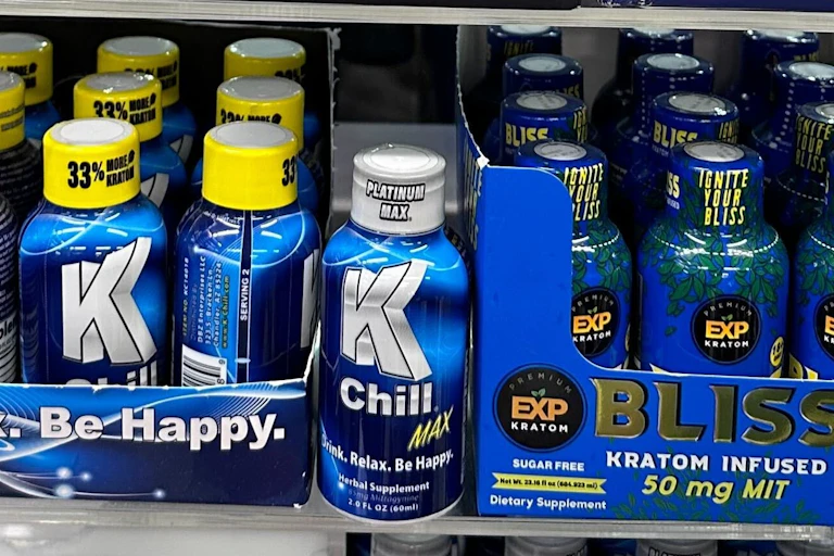 A photo of a shelf filled with bottles of supplements containing kratom.