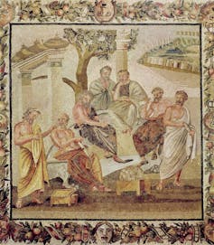 A scene of seven men in toga-like garments sitting and standing around a tree.