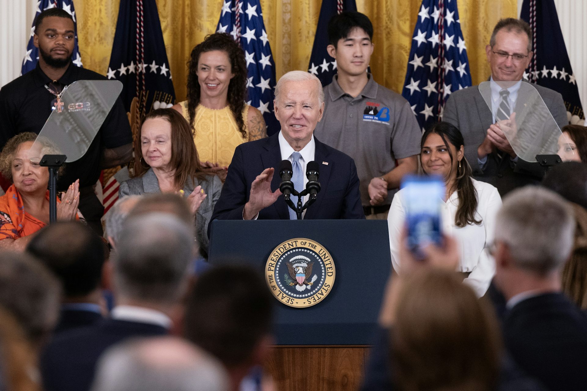 Man at podium surrounded by supporters