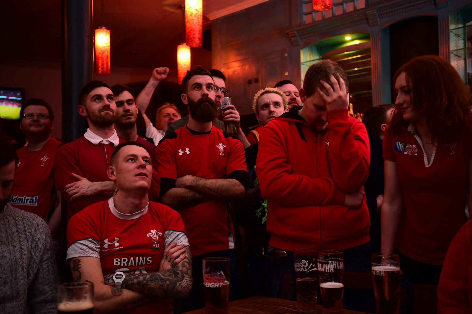 A group of Wales rugby fans in red looking disconsolate