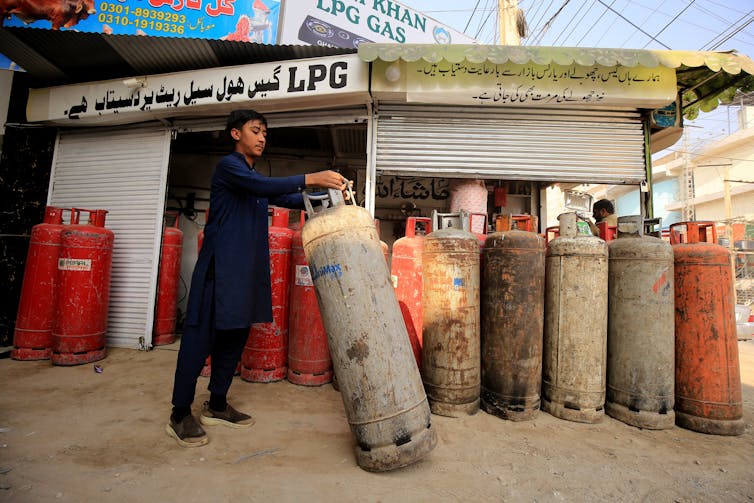 A man shifts large canisters of gas into a row.