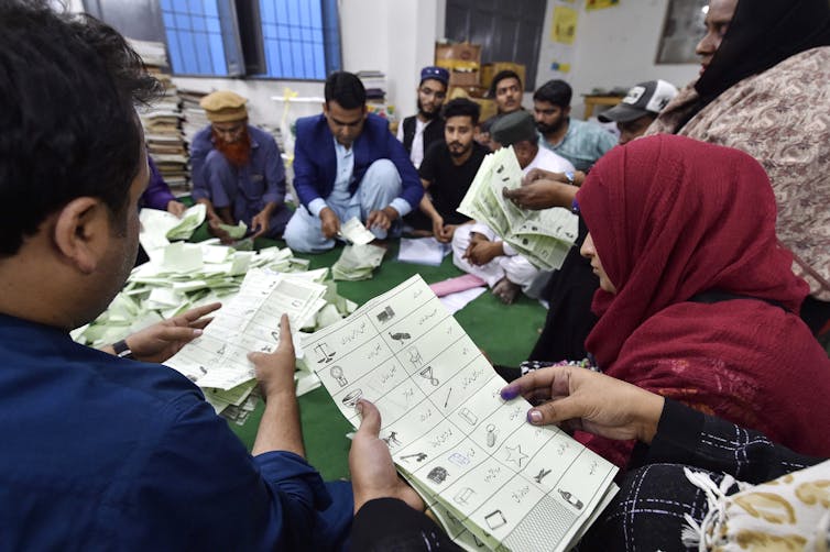 Polling officers sat on the floor counting ballots at a polling station.