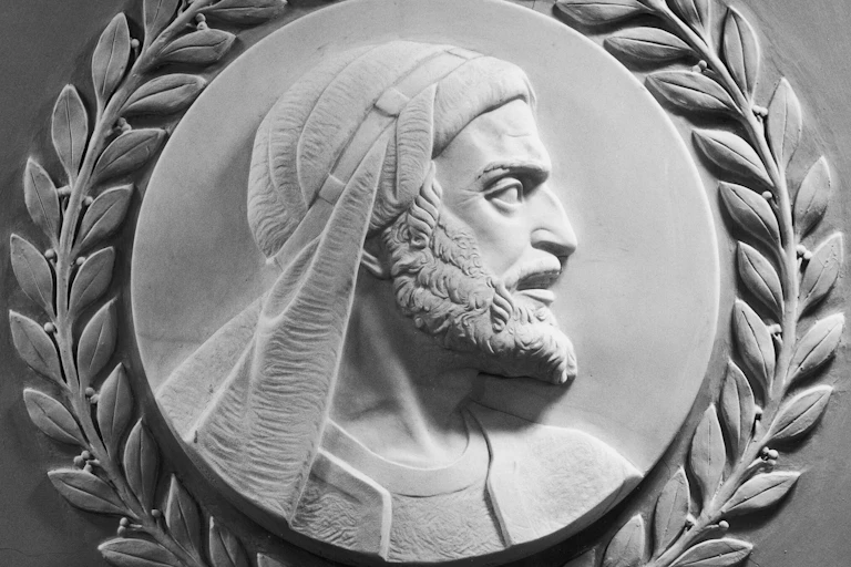 A white marble carving of a man with a beard, headscarf and a serious expression, looking off to the right.