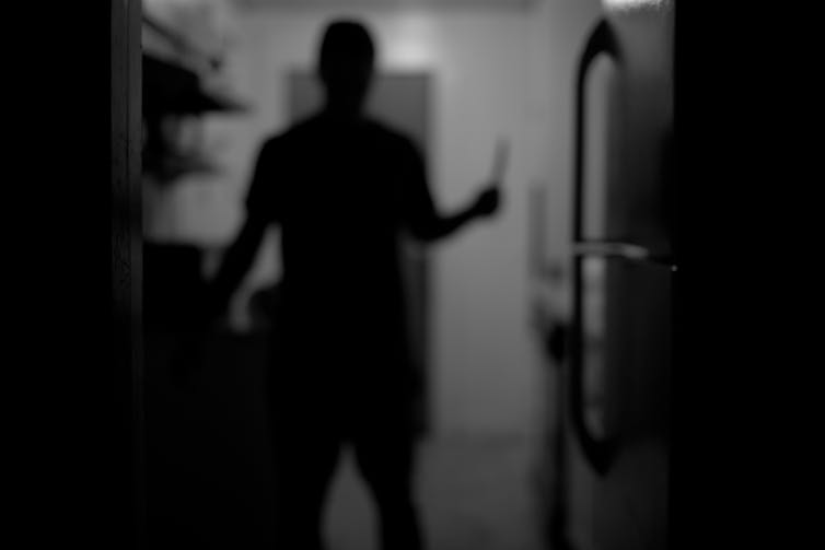 A blurry, dark black-and-white picture of a figure holding what could be a knife, or something else entirely
