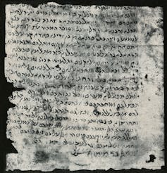 A black and white image of an old, worn parchment covered in letters in black ink.