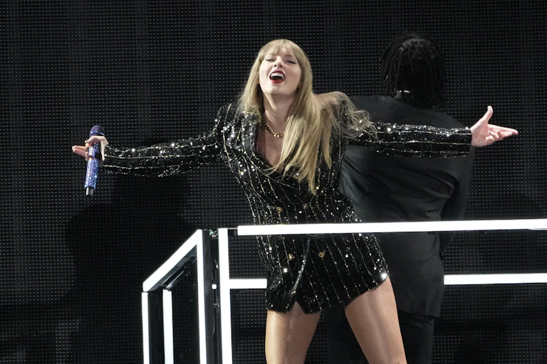 A blonde woman in bedazzled pinstripe jacket smiling to the crowd