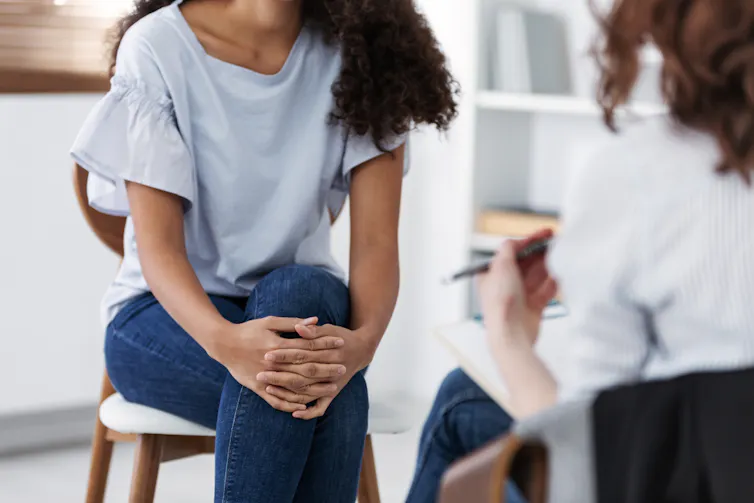 Young woman in therapy session with female therapist, both anonymous