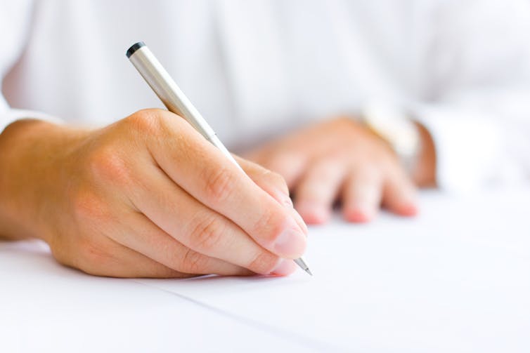 Man signing paper document with pen