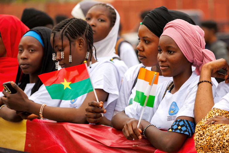 A groupof women holding a banner and small flags at a rally