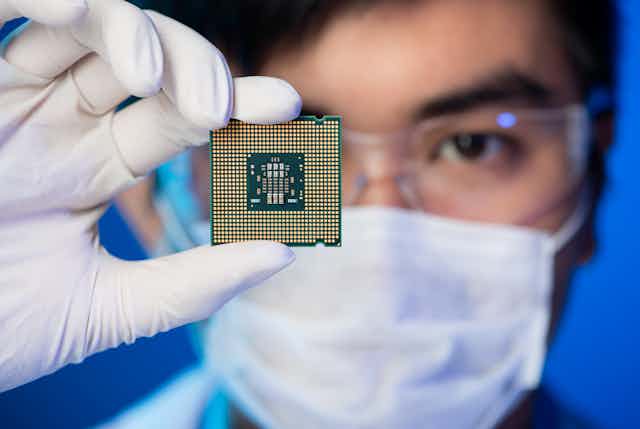 Cropped image of an engineer showing a computer microchip in the foreground