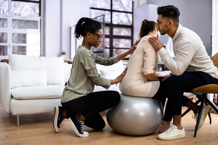 A doula massaging a pregnant woman's back