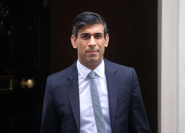The prime minister of the UK in a dark grey suit and tie.
