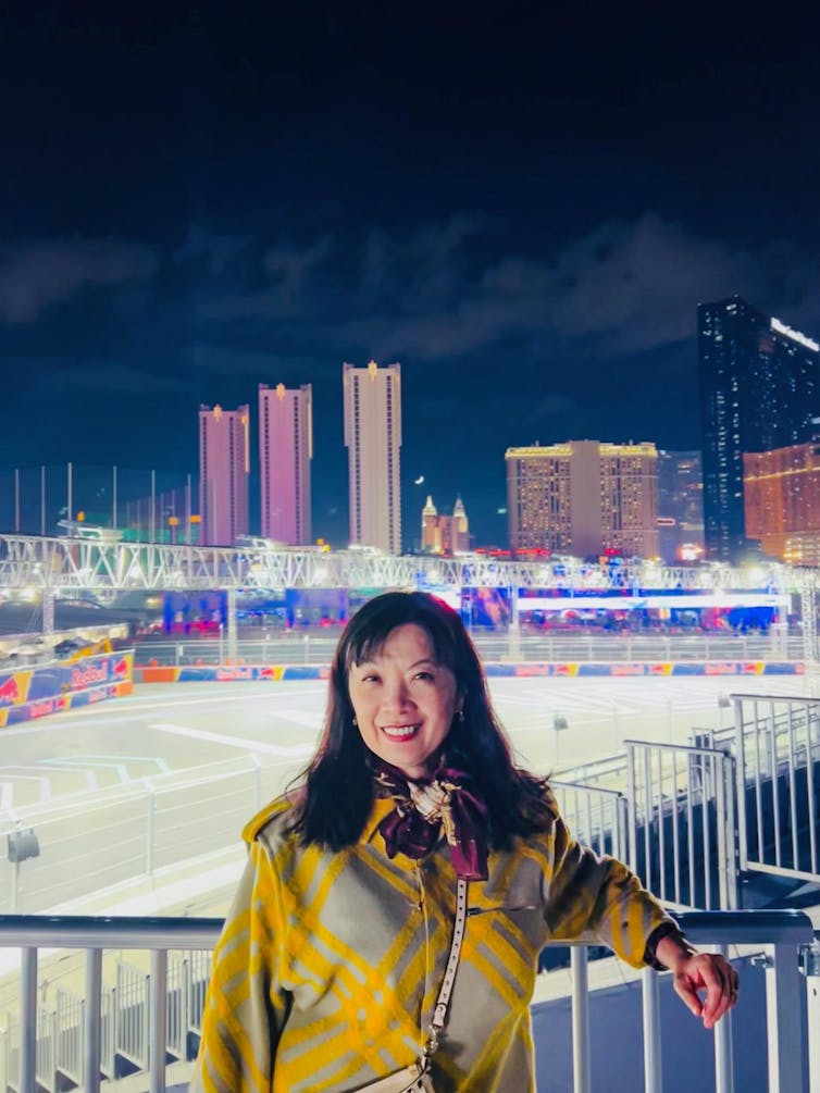 A smiling professor is illuminated by bright lights in a nighttime photo taken at a Formula 1 event in Nevada.