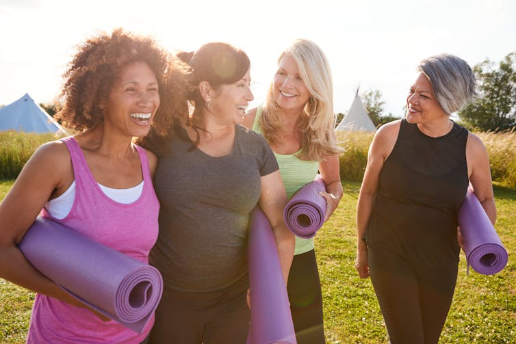 Group of women outdoors in athletic clothes carrying yoga mats