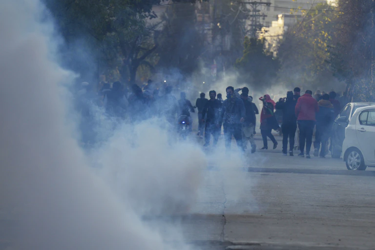 A group of protesters are seen with billowing smoke around them.