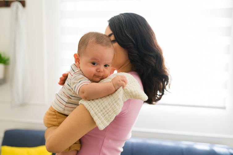 A woman pats her baby while she or she rests on on her shoulder