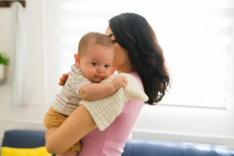A woman pats her baby while she or she rests on on her shoulder