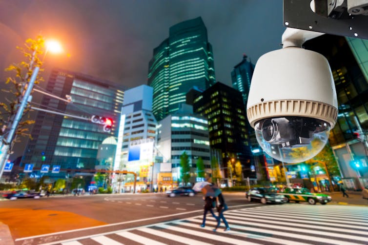 a close-up of a security camera with a city at night in the background