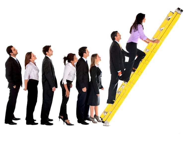 A group of men and women in business wear stand in line waiting to climb a ladder
