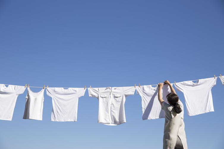 A woman hanging out white clothes on a laundry line.
