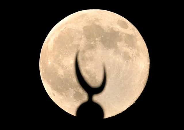 A bright moon illuminates a crescent dome.