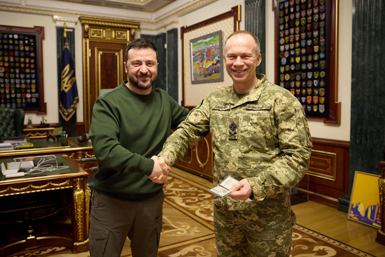 Ukrainian president Volodymyr Zelensky, smiles as he shakes hands with his new commander-in-chief Oleksandr Syrskyi.