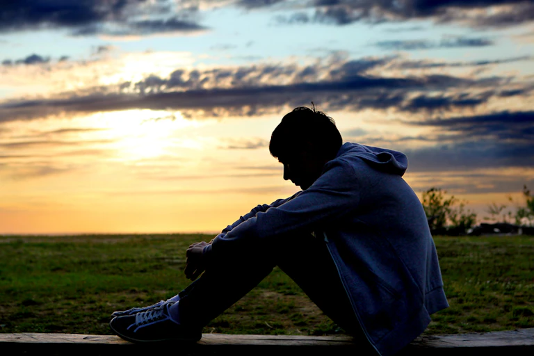 Silhouette de jeune homme devant un lac
