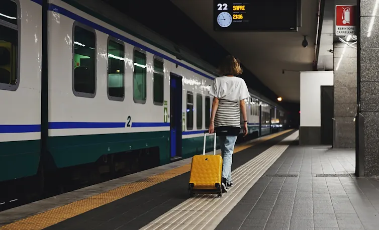 Jeune femme qui traverse la gare avec une valise