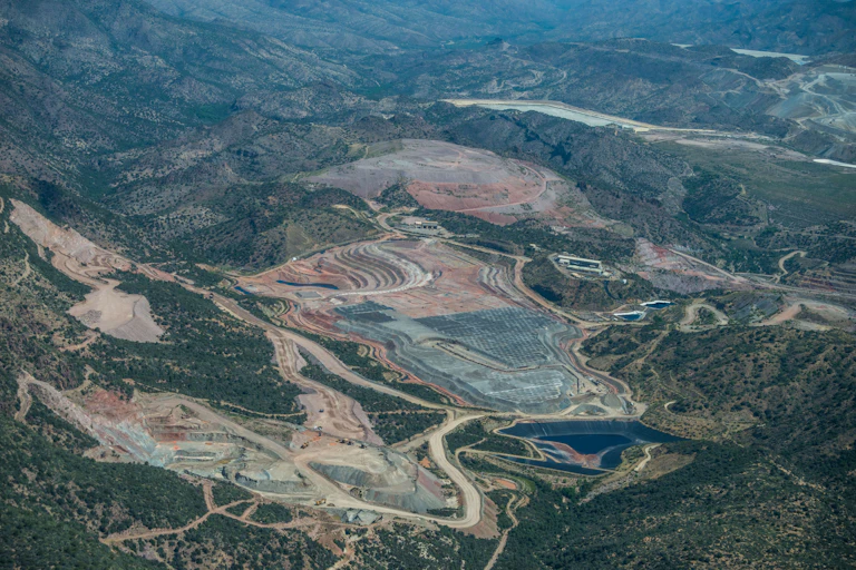Large swaths of exposed red dirt surrounded by forested land.