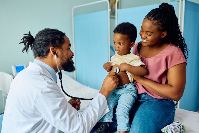A Black doctor with a Black mother and child