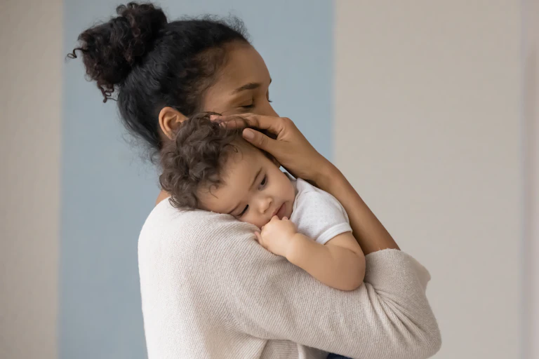 A woman rests a baby's head on her shoulder