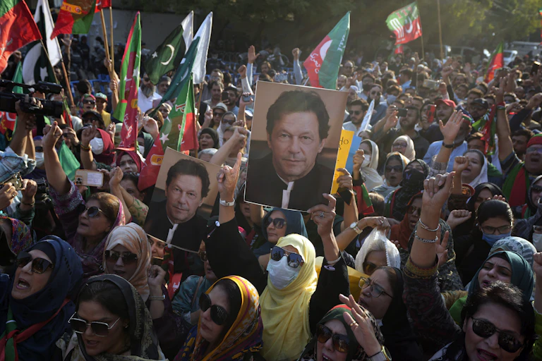 People carrying posters of a dark-haired man and waving flags stage a protest.