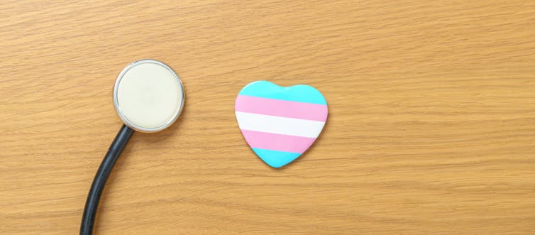 A stethoscope and a transgender flag in the shape of a heart