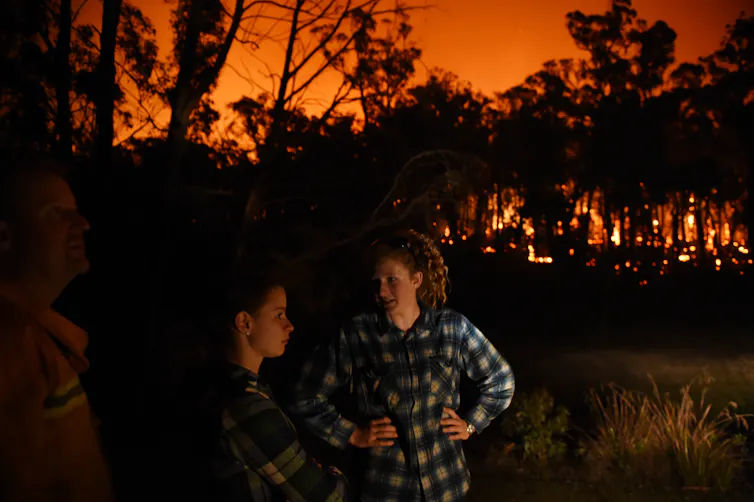 two woman stand near fire