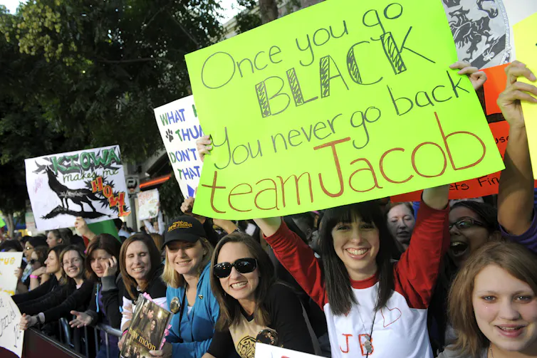 Fans hold up posters