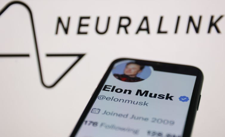 A phone screen shows a white page that says 'Elon Musk,' positioned below an abstract black design and the word 'NEURALINK.'