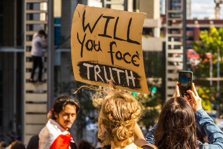 climate protestor holding sign about facing truth