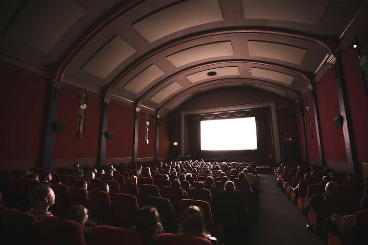 People watching cinema inside a packed theatre hall
